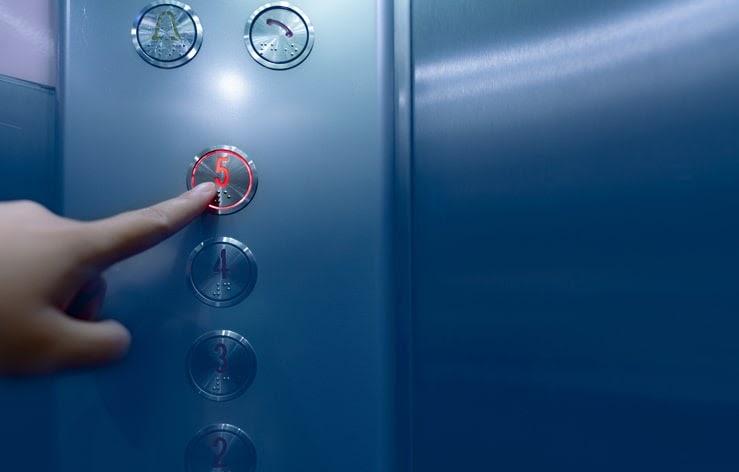 エレベーターの5階のボタンを押す人の画像
