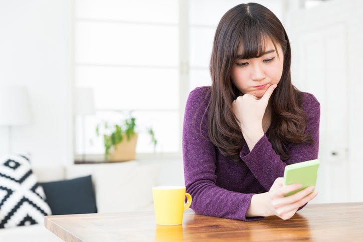スマートフォンを見て考える女性