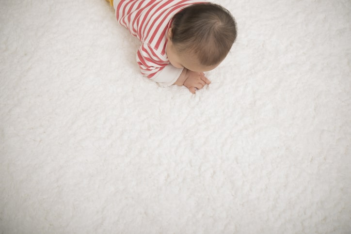 白いカーペットの上に赤ちゃんがいる様子